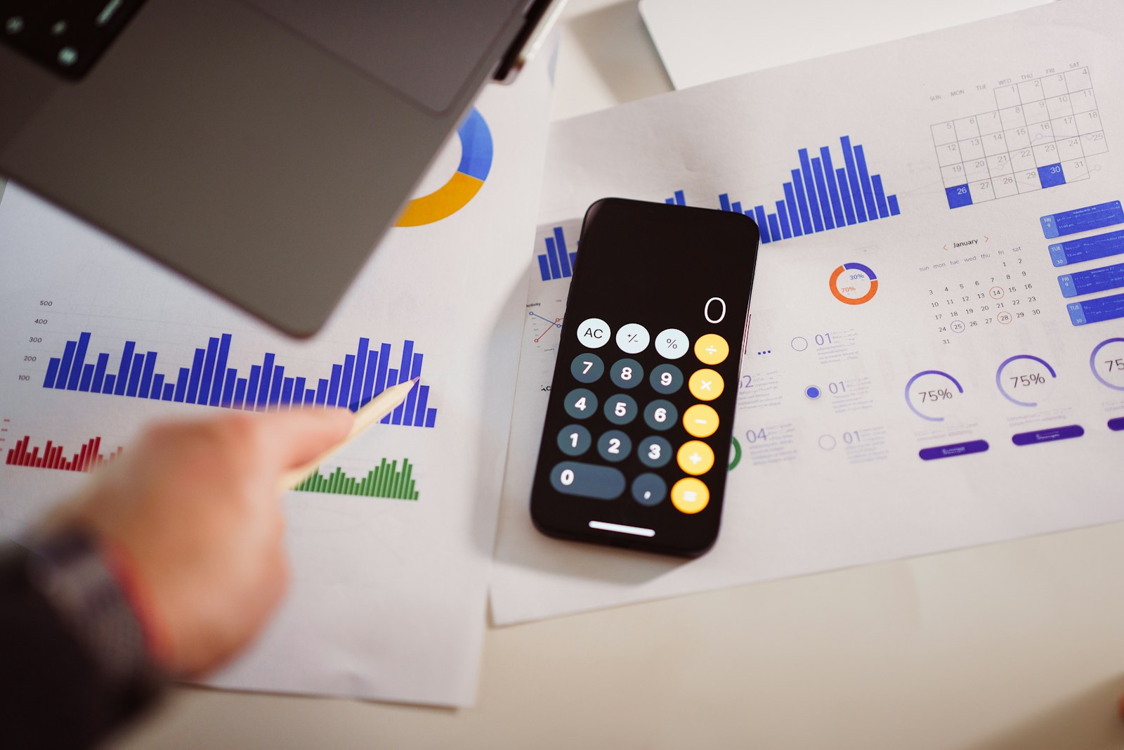 A calculator beside a laptop on a worktable